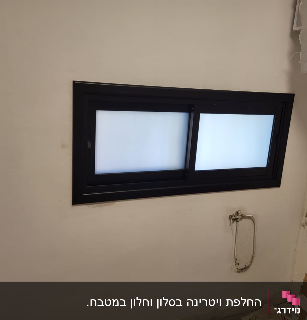 חלון אלומיניום עם מסגרת כהה על קיר לבן
